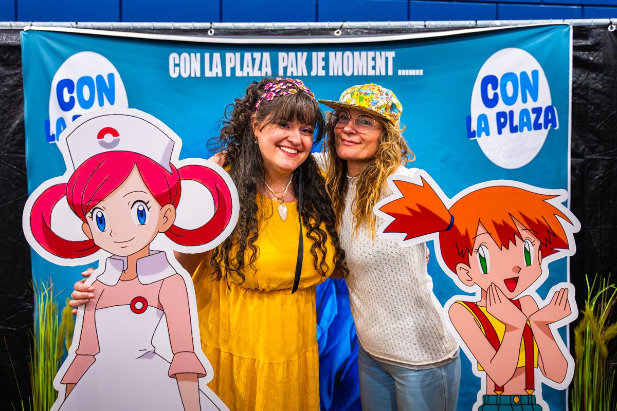 Bezoekers poseren lachend bij het Con La Posta fotodoek met Pokémon-figuren