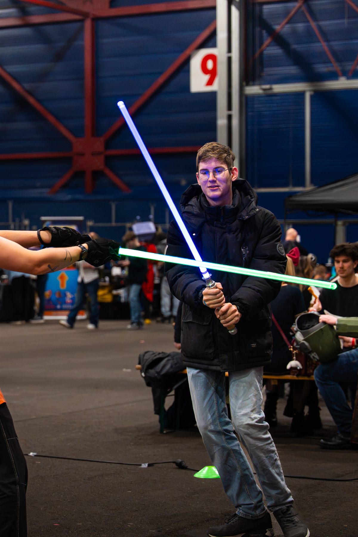 Twee bezoekers duelleren met blauwe en groene lightsabers tijdens Con La Posta